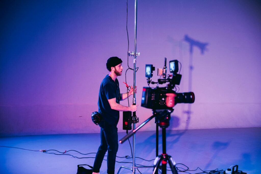 Professional cinematographer adjusting camera equipment on set with vibrant lighting.